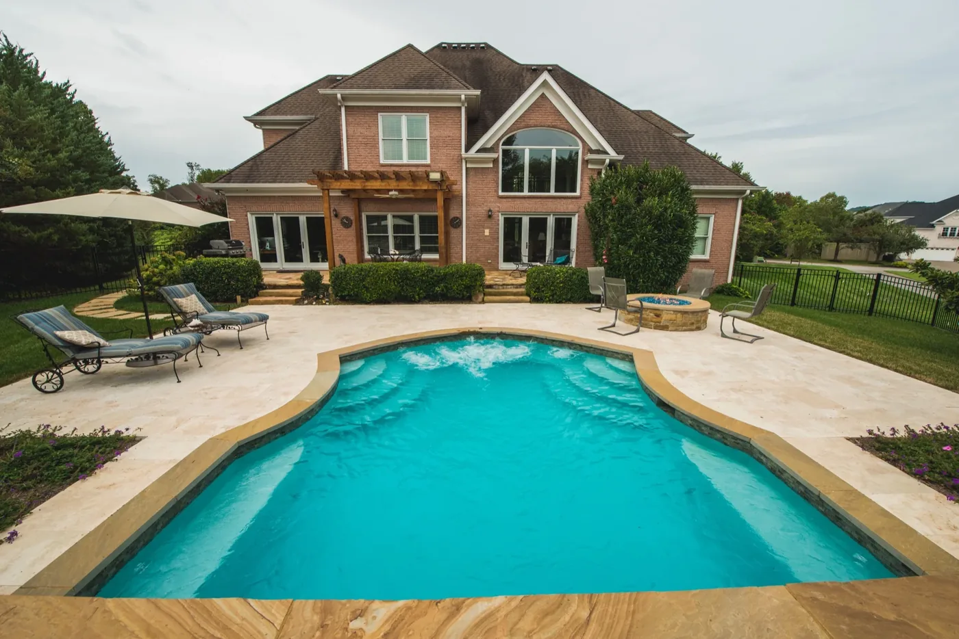 Full backyard overview showing pool, travertine deck, pergola, and fire pit at Francis Residence