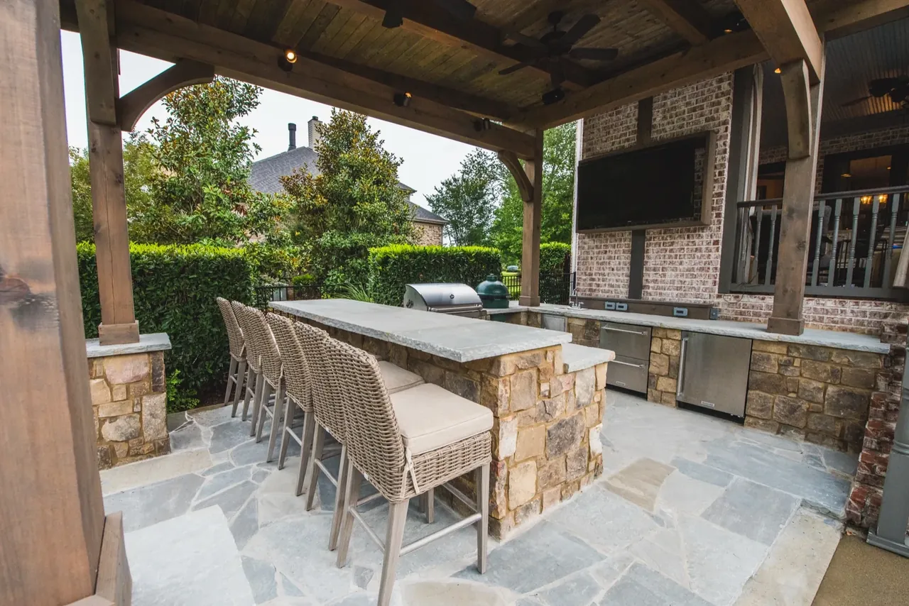 Custom outdoor kitchen and pergola adjacent to a luxury pool in a Nashville backyard