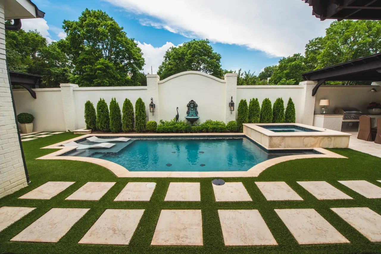 Elegant formal pool with integrated spa, stone fountain wall, and travertine decking in Nashville